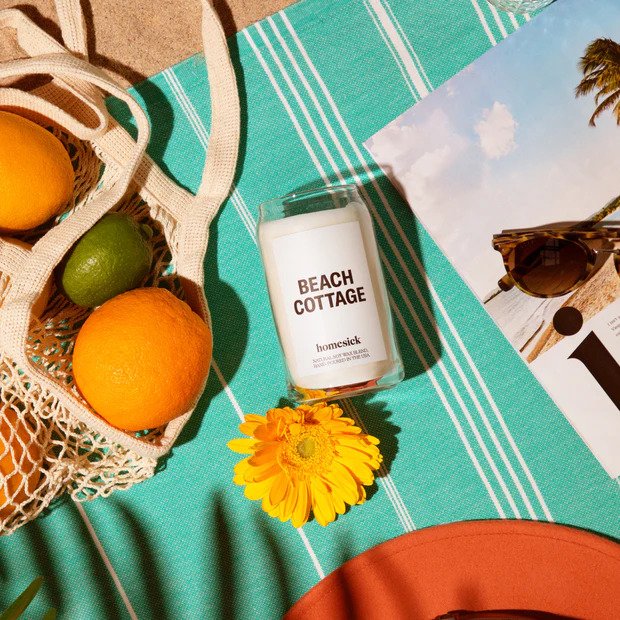 A candle on a picnic mat on the beach