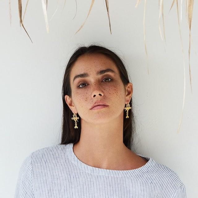 A lady wearing a pair of golden earrings