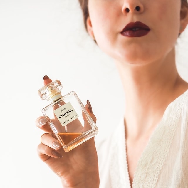 A lady opening the cap of a perfume bottle